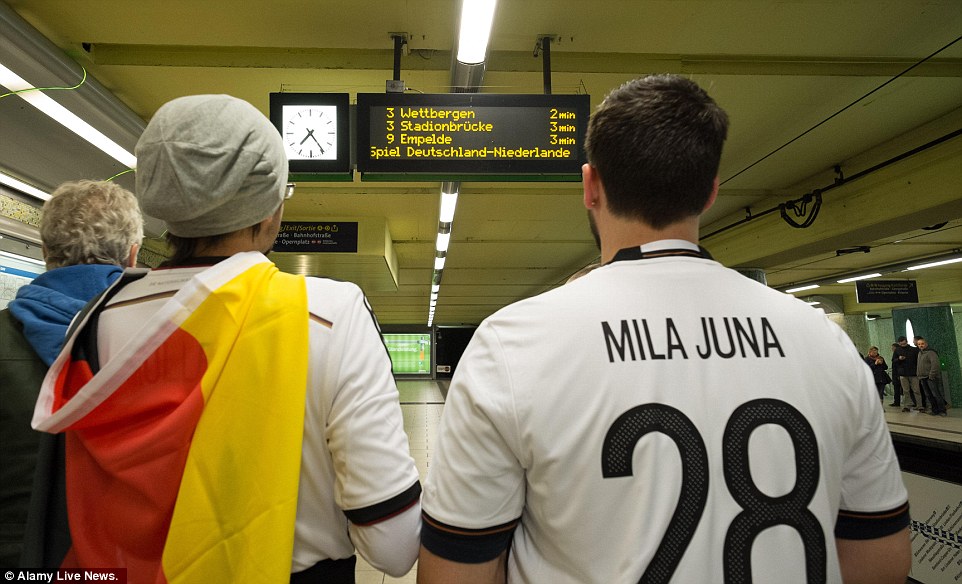 Two German football fans are pictured checking departure boards in an underground station in Hanover 