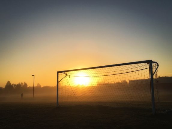 person jogging near soccer goal during sunrise 149356